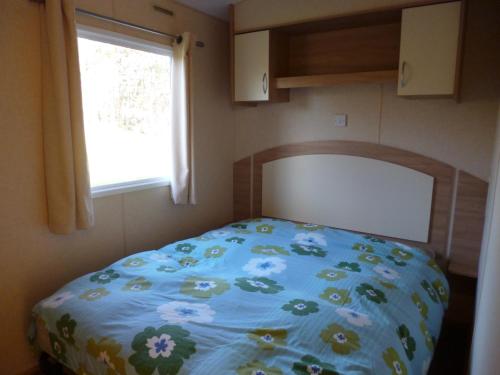 een bed in een kleine kamer met een raam bij Chalet in Wilbertoord