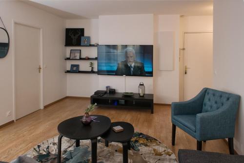 a living room with a tv and a blue chair at ILodge Primia in Chessy