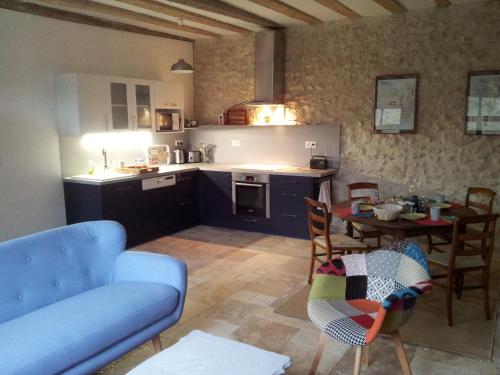 une cuisine et une salle à manger avec une table et un canapé bleu dans l'établissement Le Moulin du Bourg, à Épeigné-les-Bois
