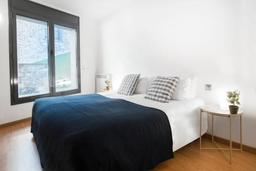 a white bedroom with a large bed and a window at Font del Ferro Apartments in El Tarter