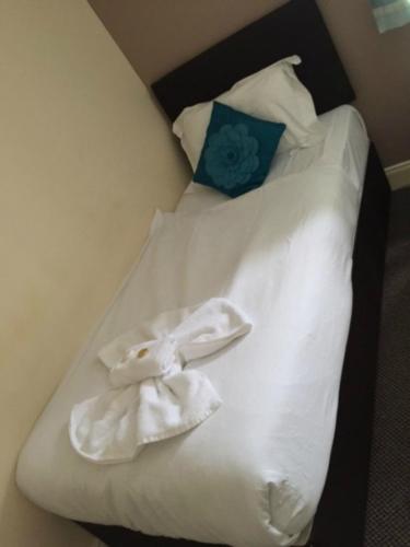 a bed with white sheets and a blue pillow at The Waverley Guest House in Inverness