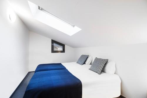 a bedroom with a white bed with a blue blanket at Font del Ferro Apartments in El Tarter