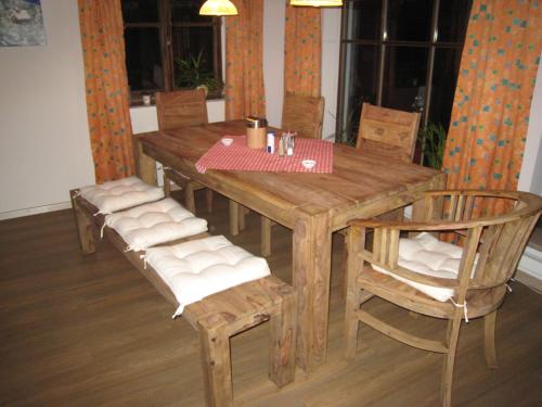 einen Holztisch mit Stühlen und einem Tisch sowie einem Tisch und einem Chairsktop in der Unterkunft Pension Schihütte in Oberstaufen