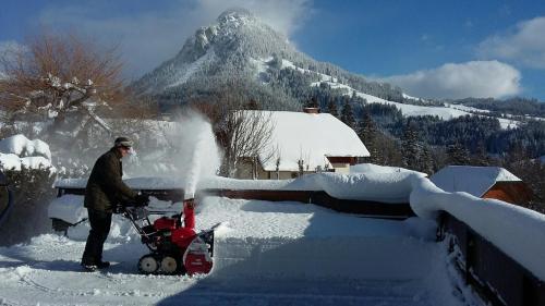 a man with a snow blower in front of a mountain at Ferienwohnung Hierzegger in Tauplitz