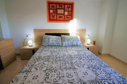 a bedroom with a bed with a blue and white bedspread at CasaTuris Playa Postiguet A113 in Alicante