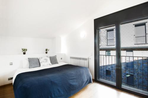 a bedroom with a bed and a large window at Font del Ferro Apartments in El Tarter