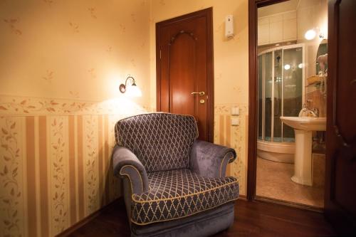 una silla sentada en una habitación con lavabo en Kupecheskiy Club Hotel, en Bor