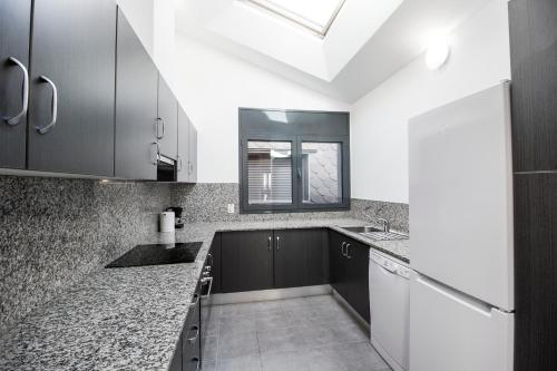 a kitchen with black and white cabinets and a window at Font del Ferro Apartments in El Tarter