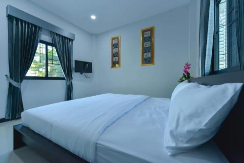 a bedroom with a white bed and two windows at Jarat Mansion in Surin