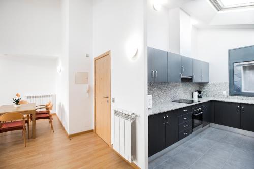 a kitchen with black and white cabinets and a table at Font del Ferro Apartments in El Tarter