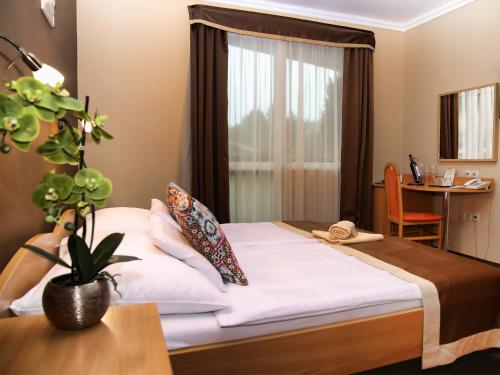 a bedroom with a bed and a table and a window at ALFA Hotel & Wellness Miskolctapolca in Miskolctapolca