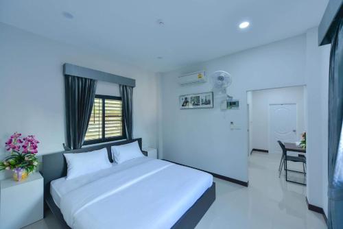 a bedroom with a large white bed and a desk at Jarat Mansion in Surin