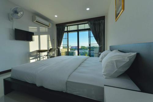 - une chambre avec un grand lit blanc et un balcon dans l'établissement Jarat Mansion, à Surin