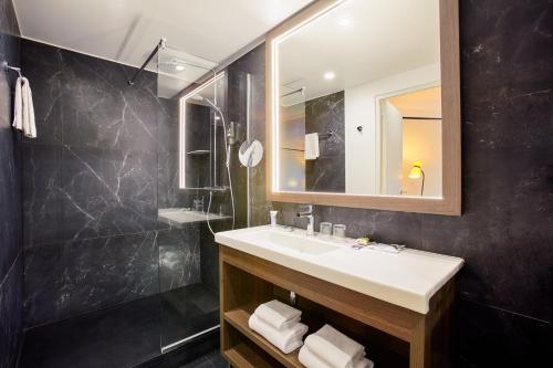La salle de bains est pourvue d'un lavabo et d'un miroir. dans l'établissement Mercure Paris Saint-Ouen, à Saint-Ouen