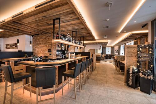 a bar in a restaurant with black chairs and wooden walls at Hotel Eldorado in Ischgl