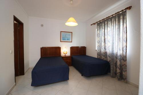 アルブフェイラにあるVilla Gonçalvesのベッドルーム1室(ベッド2台、窓付)