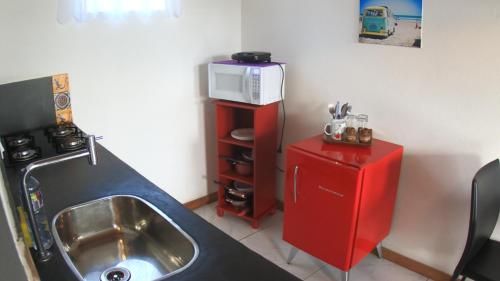 馬烈席亞斯的住宿－Suites Vida Mansa，厨房配有水槽和红色冰箱上的微波炉