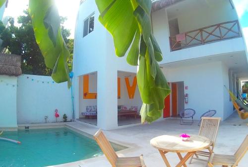 ein Haus mit einem Pool, einem Tisch und Stühlen in der Unterkunft Hostel Humanity in Puerto Morelos