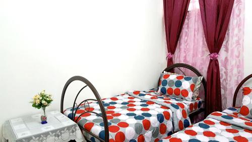 a bedroom with two beds and a table with flowers at Mahkota Cheras Sweet Condo 1-14 pax near MRT to KL in Kuala Lumpur
