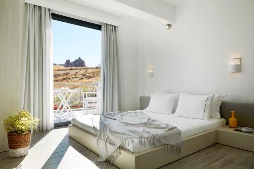 a white bedroom with a bed and a large window at Eleia Seafront Rooms & Villas in Petra