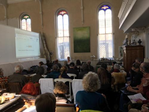 un grupo de personas sentadas en una sala con una presentación en Church Des Artistes, en Kingston