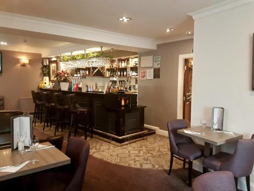 a restaurant with a bar and some tables and chairs at Fairburn Hotel in Mauchline