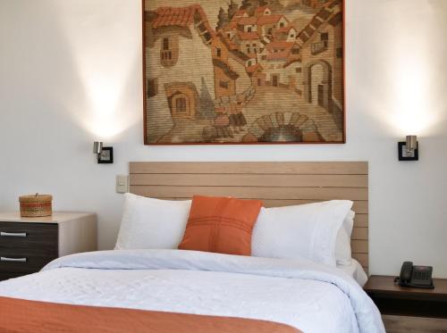 a bedroom with a bed with an orange pillow at Hotel La Fuente in Coquimbo