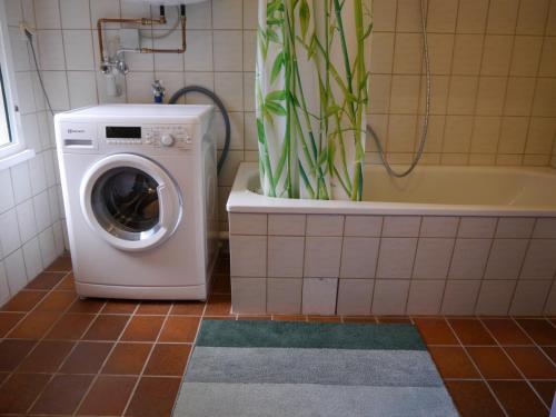 a washing machine in a bathroom next to a bath tub at Haus Honigstal Landhaus Café in Wuppertal