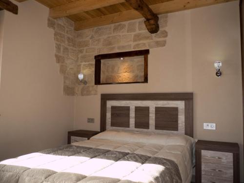a bedroom with a bed and a stone wall at Apartamentos La Fabrica in Villaluenga de la Vega