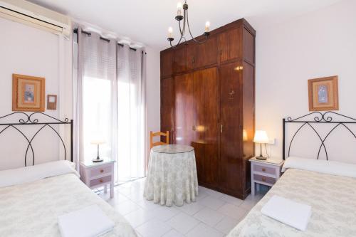 a bedroom with two beds and a wooden cabinet at Pension Mesones in Granada