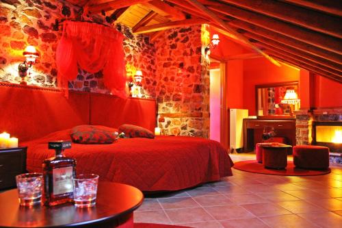 a bedroom with a red bed in a stone wall at Patriko Mountain Chalet in Palaios Agios Athanasios