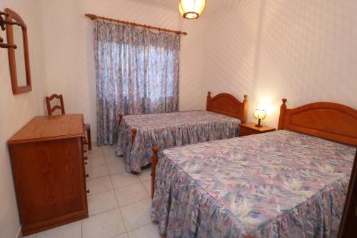 a bedroom with two beds and a dresser and a window at Villa Estela in Albufeira