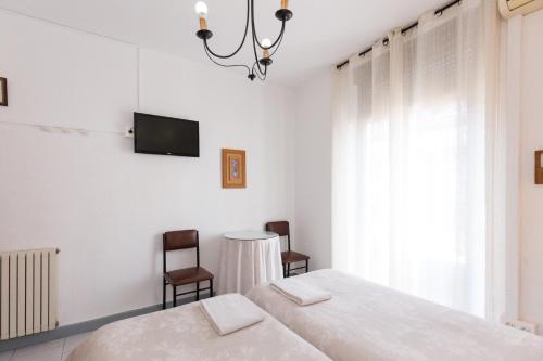 a bedroom with a bed and two chairs and a tv at Pension Mesones in Granada