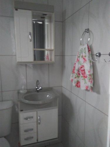 a small bathroom with a sink and a mirror at Suítes Para Casal in Bertioga