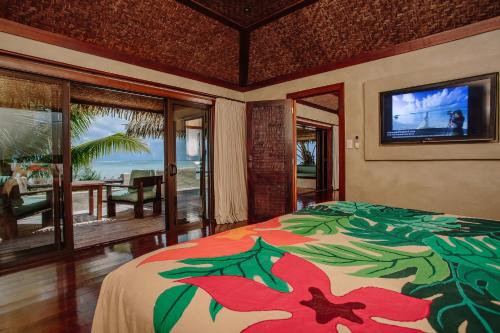 a bedroom with a bed and a television in it at Pacific Resort Aitutaki - Adults Only in Arutanga