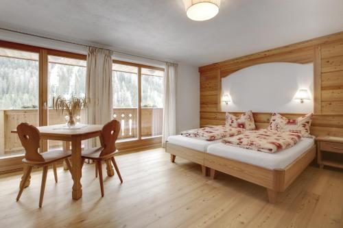 a bedroom with a bed and a table with chairs at Ciasa Medalghes in San Martino in Badia