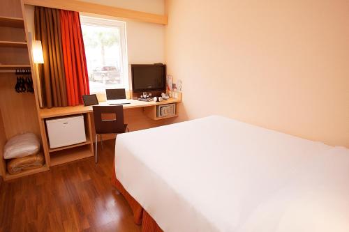 a bedroom with a bed and a desk with a computer at ibis Curitiba Aeroporto in São José dos Pinhais