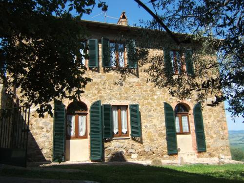 una antigua casa de piedra con ventanas con persianas verdes en Villa Santa Maria, en Montalcino