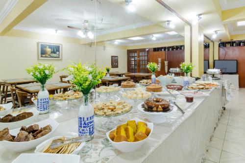 ein Buffet mit Speisen auf einem langen Tisch in der Unterkunft Hotel Acacia in São Caetano do Sul