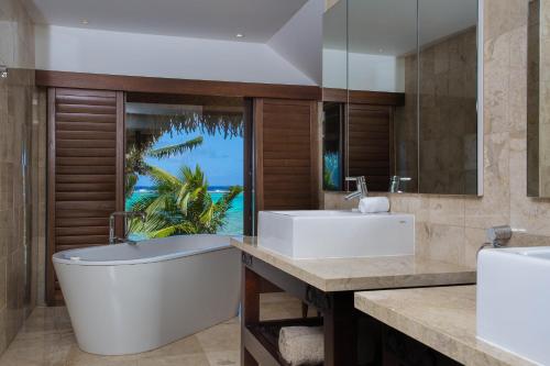 uma casa de banho com 2 lavatórios, uma banheira e uma janela em Te Manava Luxury Villas & Spa em Rarotonga