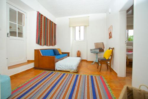 sala de estar con silla azul y alfombra en Casinha da Aldeia, en Melides