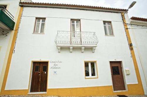 a white house with a balcony on the side of it at Casinha da Aldeia in Melides