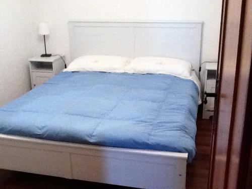 a bed with a blue comforter and two pillows at Mirtilli in Prato Nevoso