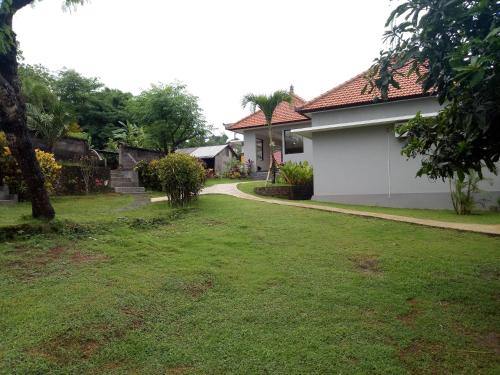 a yard with a house and a driveway at 3D Homestay in Uluwatu