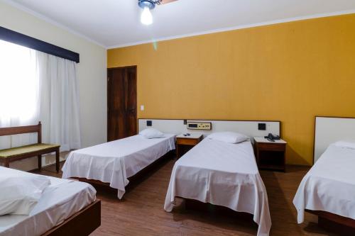 a room with two beds and a yellow wall at Hotel Acacia in São Caetano do Sul