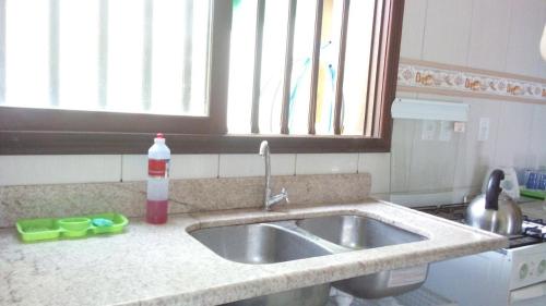 a kitchen counter with a sink and a window at Casa 3 dormitórios in Tramandaí