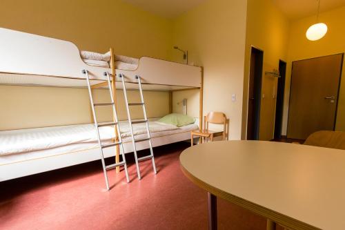 a room with a bunk bed and a table at Ostel Jugendhotel Bremervörde in Bremervörde