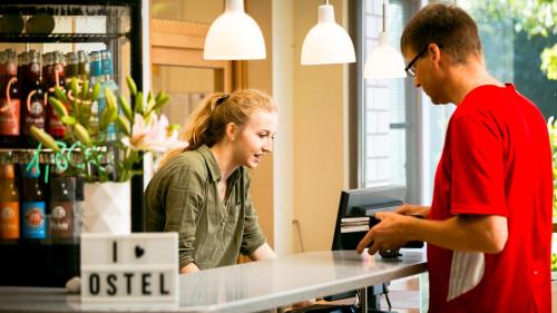 a man and a woman standing at a counter at Ostel Jugendhotel Bremervörde in Bremervörde