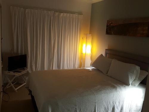 Schlafzimmer mit einem weißen Bett und einem TV in der Unterkunft Drifters Apartment in Noosaville