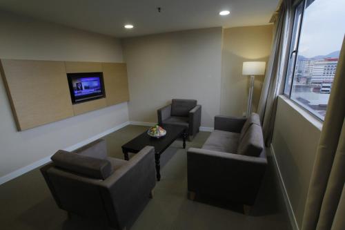 a living room with chairs and a table and a tv at Hotel Excelsior Ipoh in Ipoh